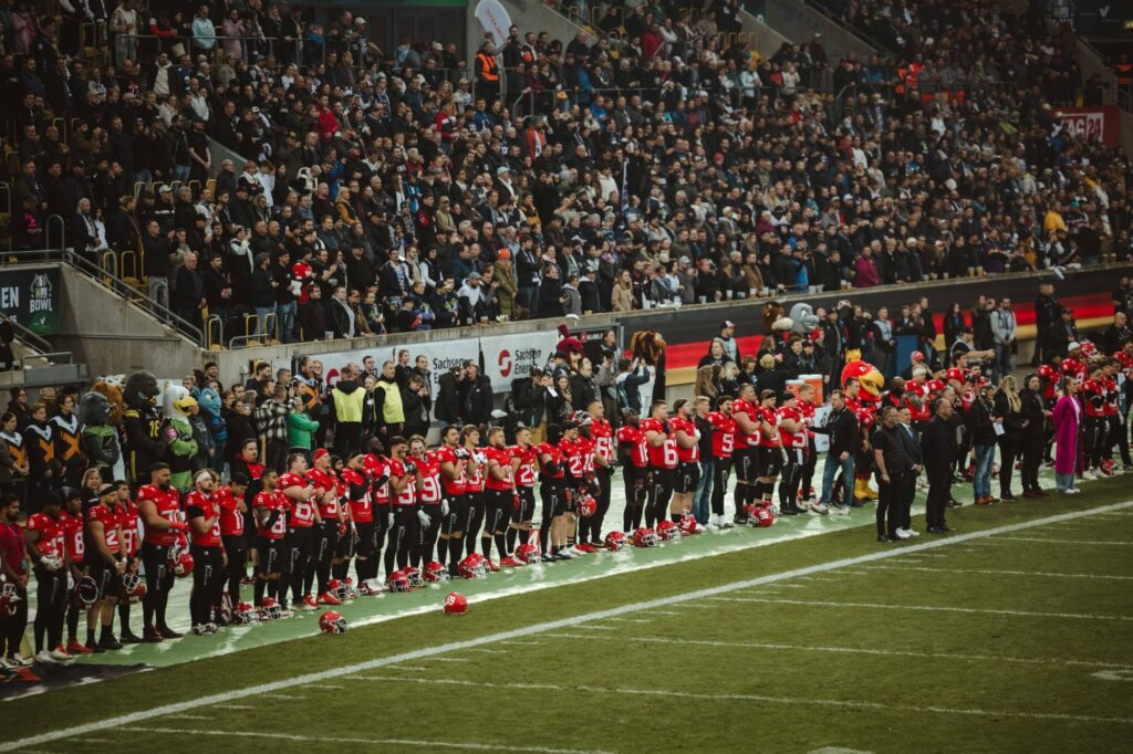 Teams und Zuschauer bei der Nationalhymne vor dem Kickoff